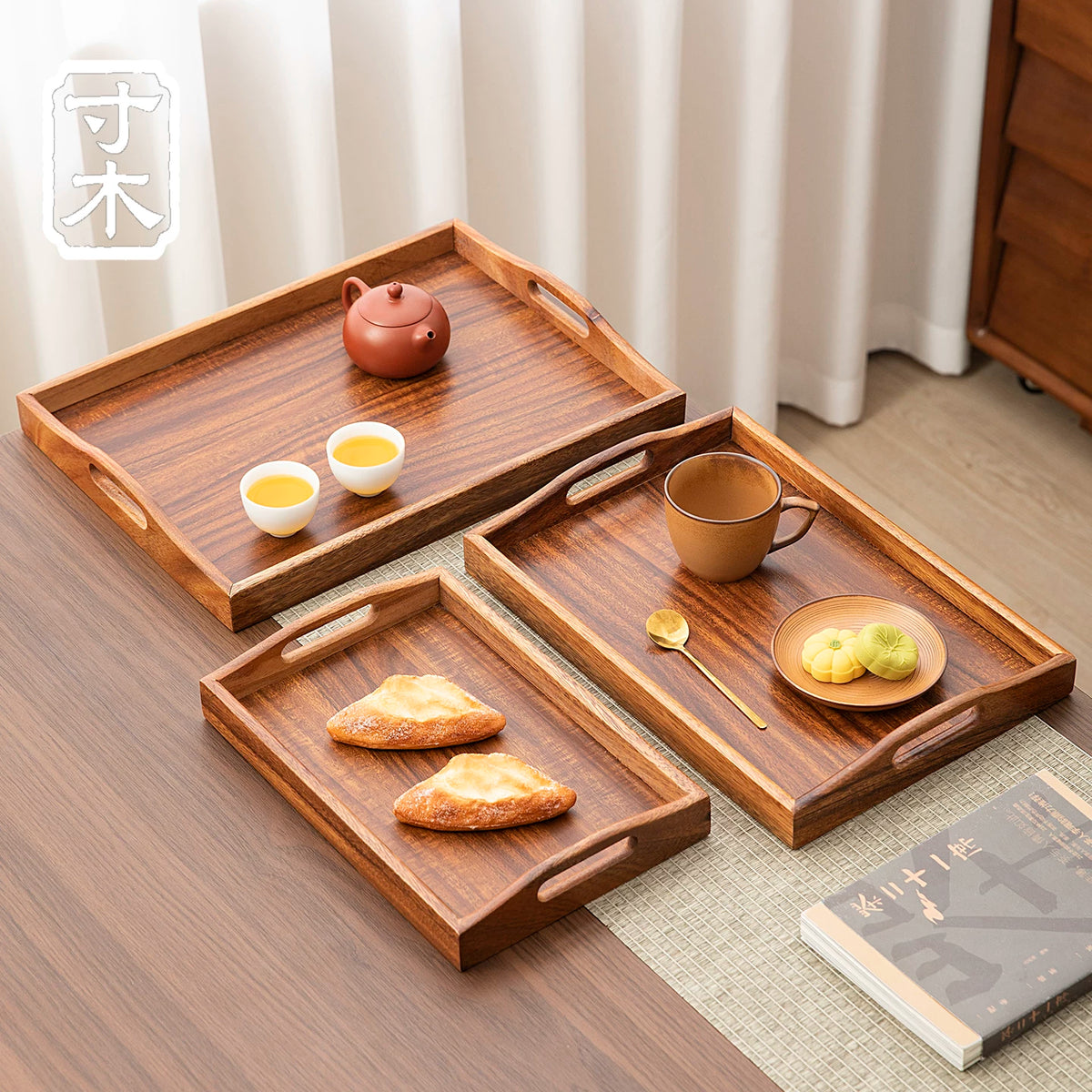 Walnut wood serving trays in three sizes arranged with tea, coffee and small plates