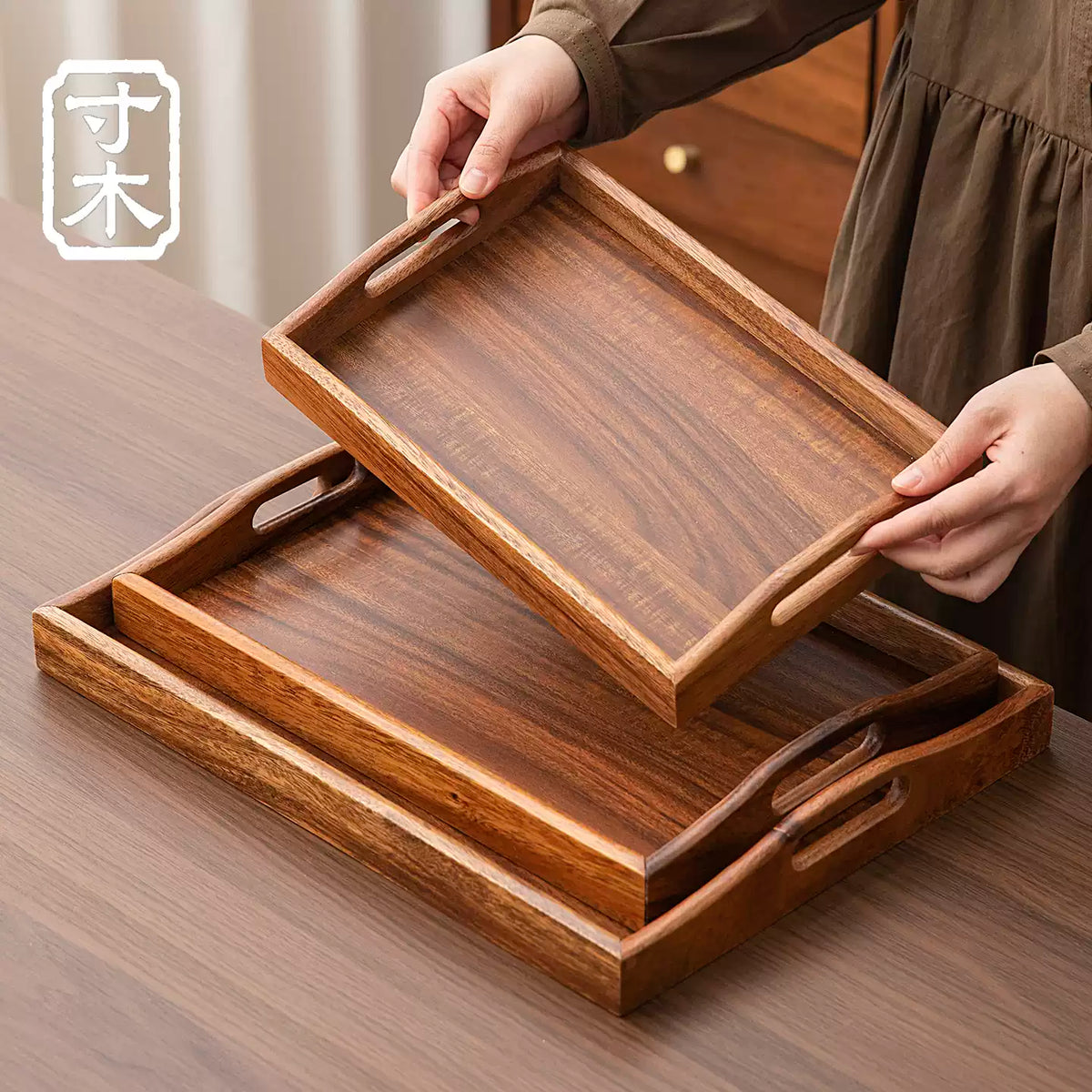 Curved-handle walnut serving trays stacked together on a wooden table
